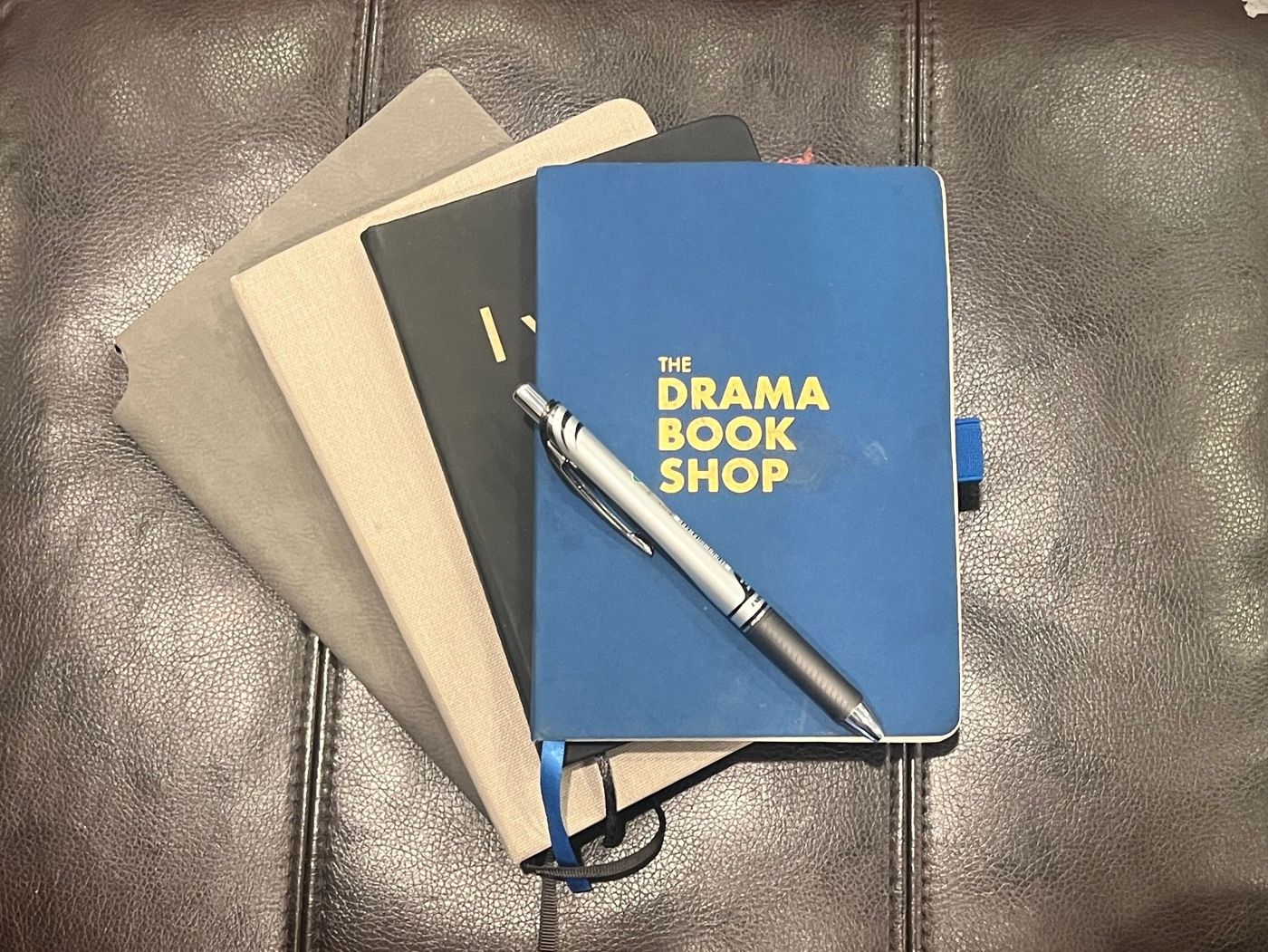 Stack of notebooks and a pen, one from The Drama Book Shop
