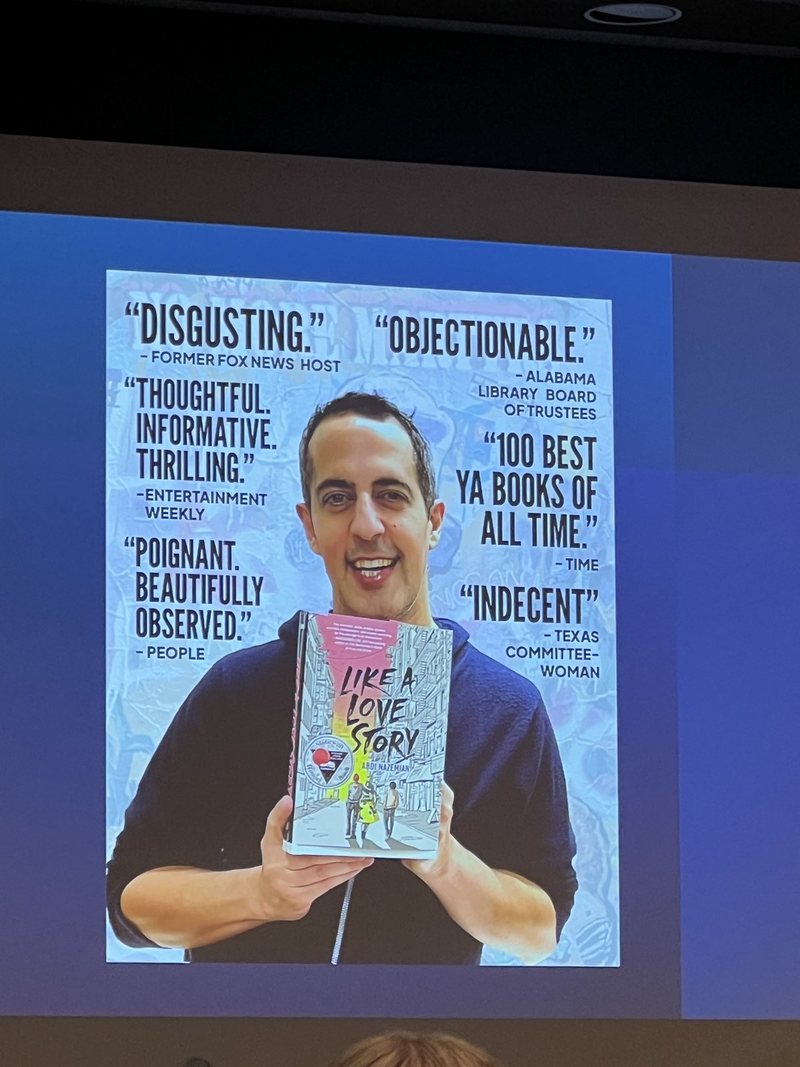Presentation slide of author Abdi Nazemian holding his book Like a Love Story, surrounded by quotes that both praise and condemn it