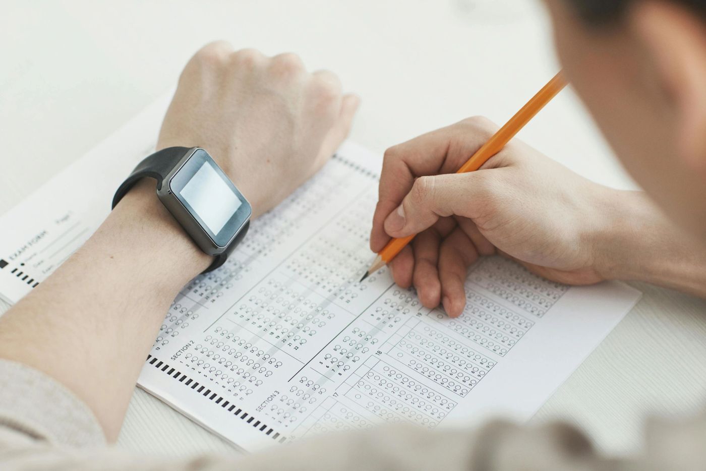 Person filling in a bubble answer sheet with a pencil