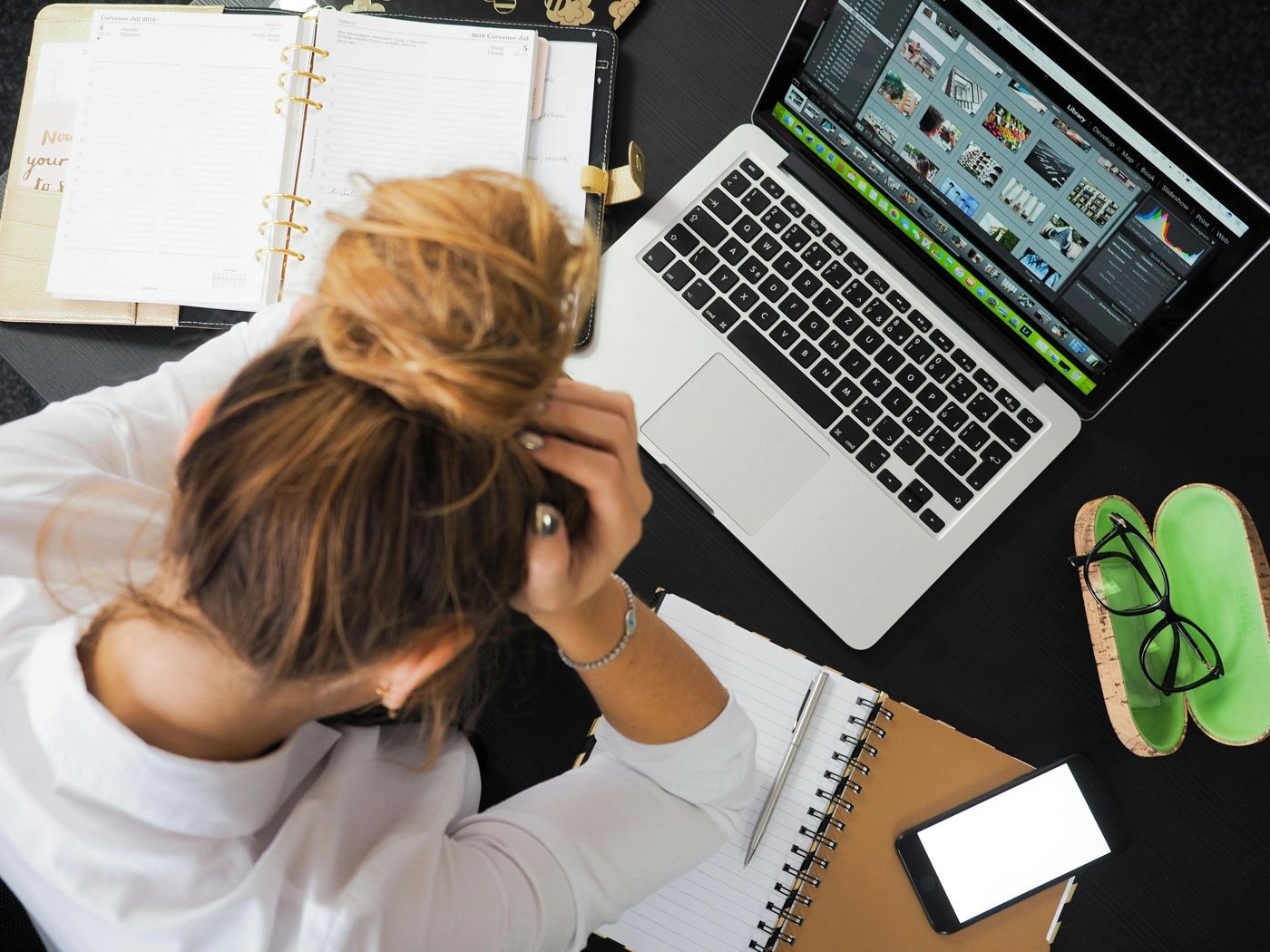 Overwhelmed person at a desk with a laptop and planner